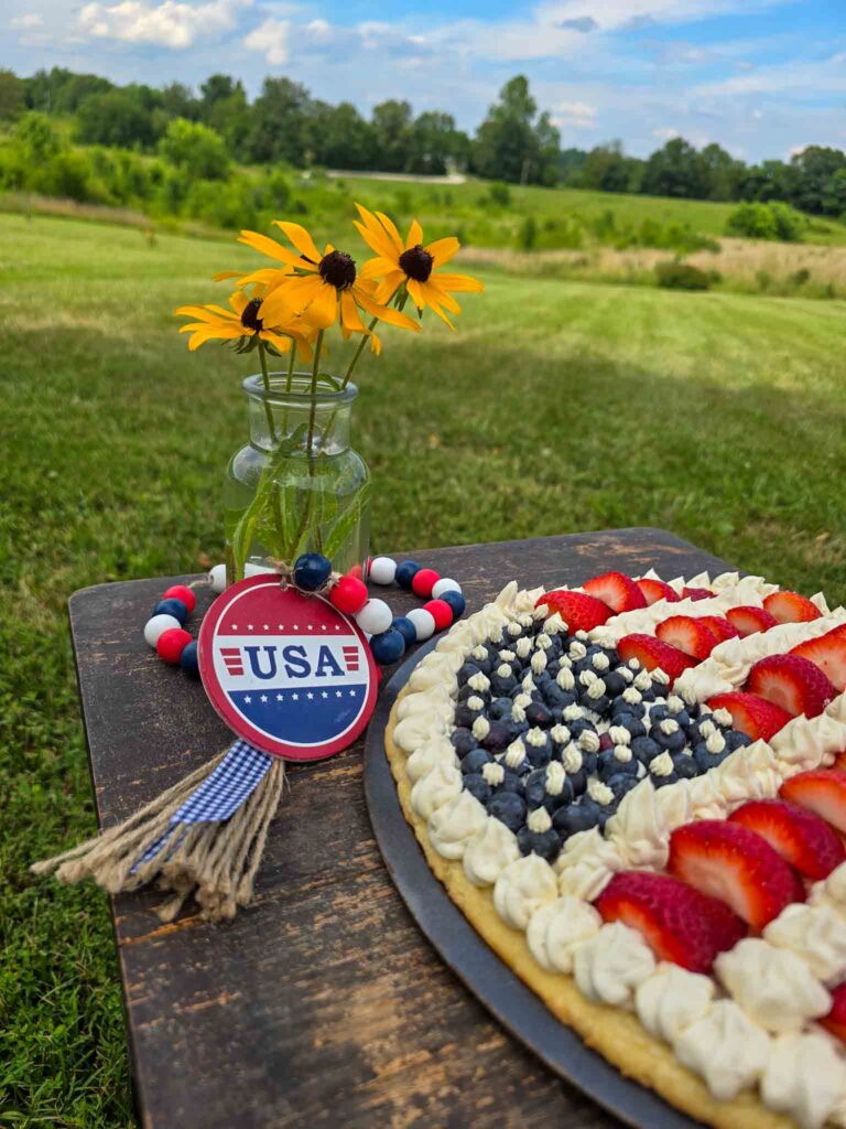 patriotic fruit pizza on table with yellow flowers in vase